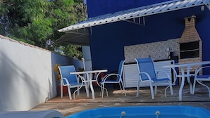 A swimming pool with a blue interior, surrounded by white chairs and a table.