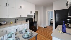 A modern kitchen with white cabinets, a black oven, and a dining area with a table set for four.
