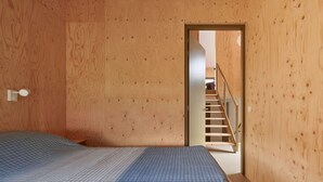 A room with a wooden floor, a bed with a patterned bedspread, and a door leading to a staircase. - 6 bedroom awesome home in Spier (Spier)