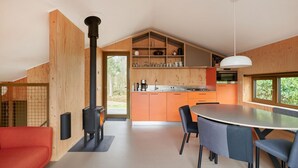 A modern kitchen with wooden cabinets, a black stove, and a dining area with a table and chairs. - 6 bedroom awesome home in Spier (Spier)
