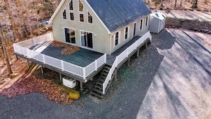 A two-story house with a porch, a small deck, and a staircase leading to the upper floor.