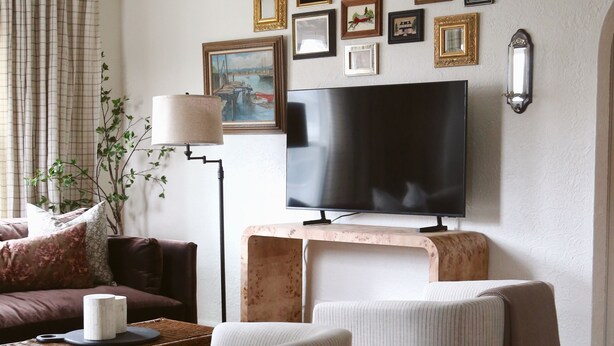 A living room with a television, framed pictures, a lamp, and a couch.