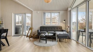 Un salon moderne avec un canapé gris, une table basse ronde et un coin repas comprenant une table et des chaises.