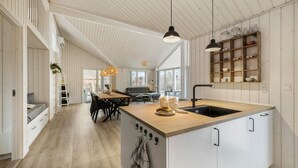 Une cuisine spacieuse dotée d’un îlot central, de planchers en bois et d’un coin repas avec un canapé et une table.