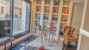 A modern living room with a glass coffee table, a red sofa, and a bookshelf filled with books.