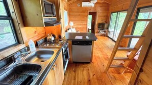 Una cucina compatta con pareti in legno, un'isola centrale e un forno a microonde integrato.