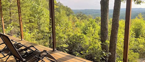 A wooden deck with a view of a forested landscape.