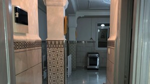 A hallway with tiled walls and a tiled floor, leading to a kitchen area with a stove and tiled backsplash. - 10 minutes from the airport and beatch beach and sandy beach  (El-Harrach)