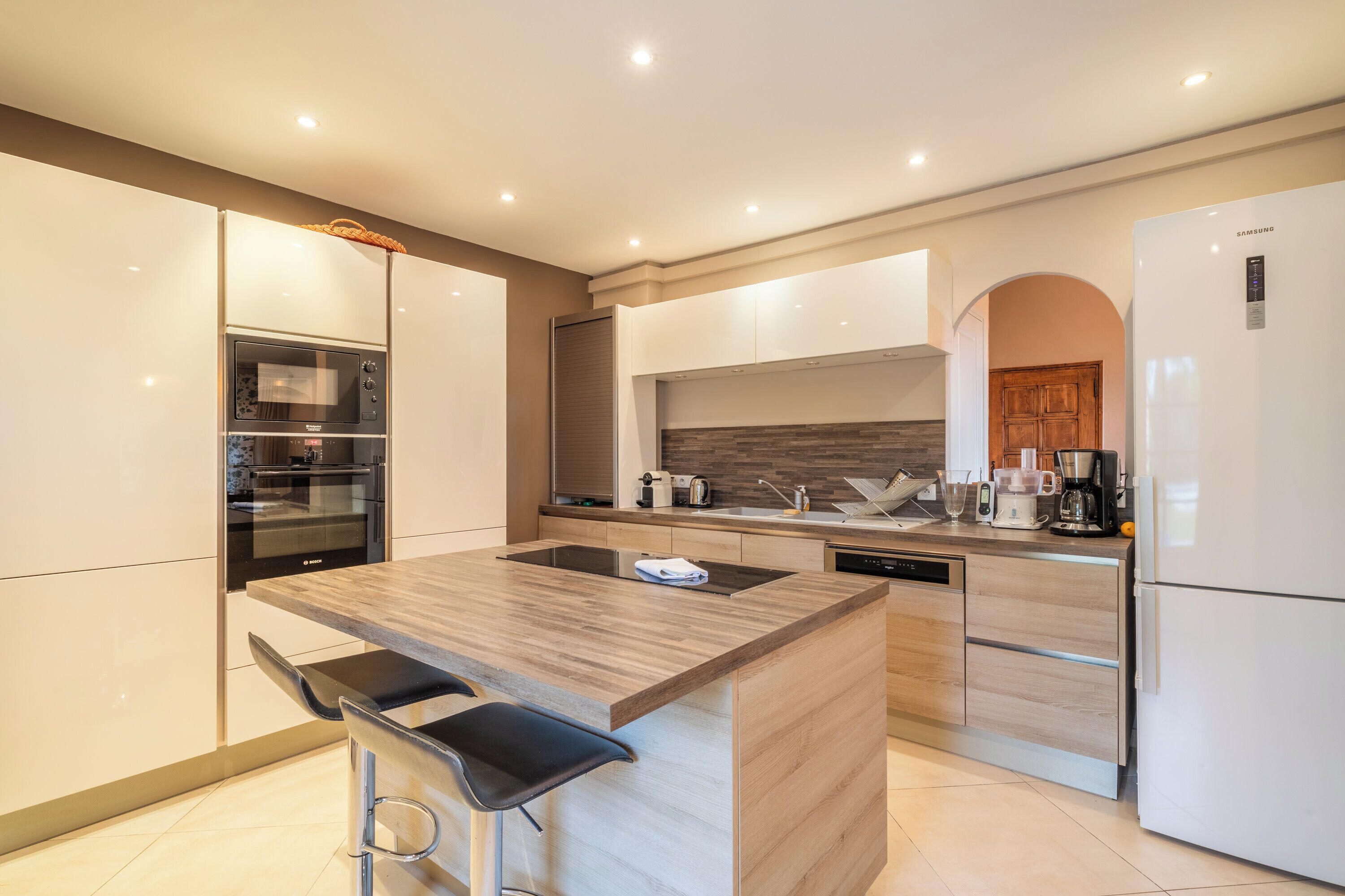 A modern kitchen with a central island, built-in appliances, and a dishwasher.