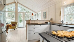 Eine moderne Küche mit einer großen Kochinsel, Holzschränken und Blick ins Freie.