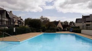 Una piscina rectangular con una escalera metálica en un lateral, rodeada por una terraza de baldosas.