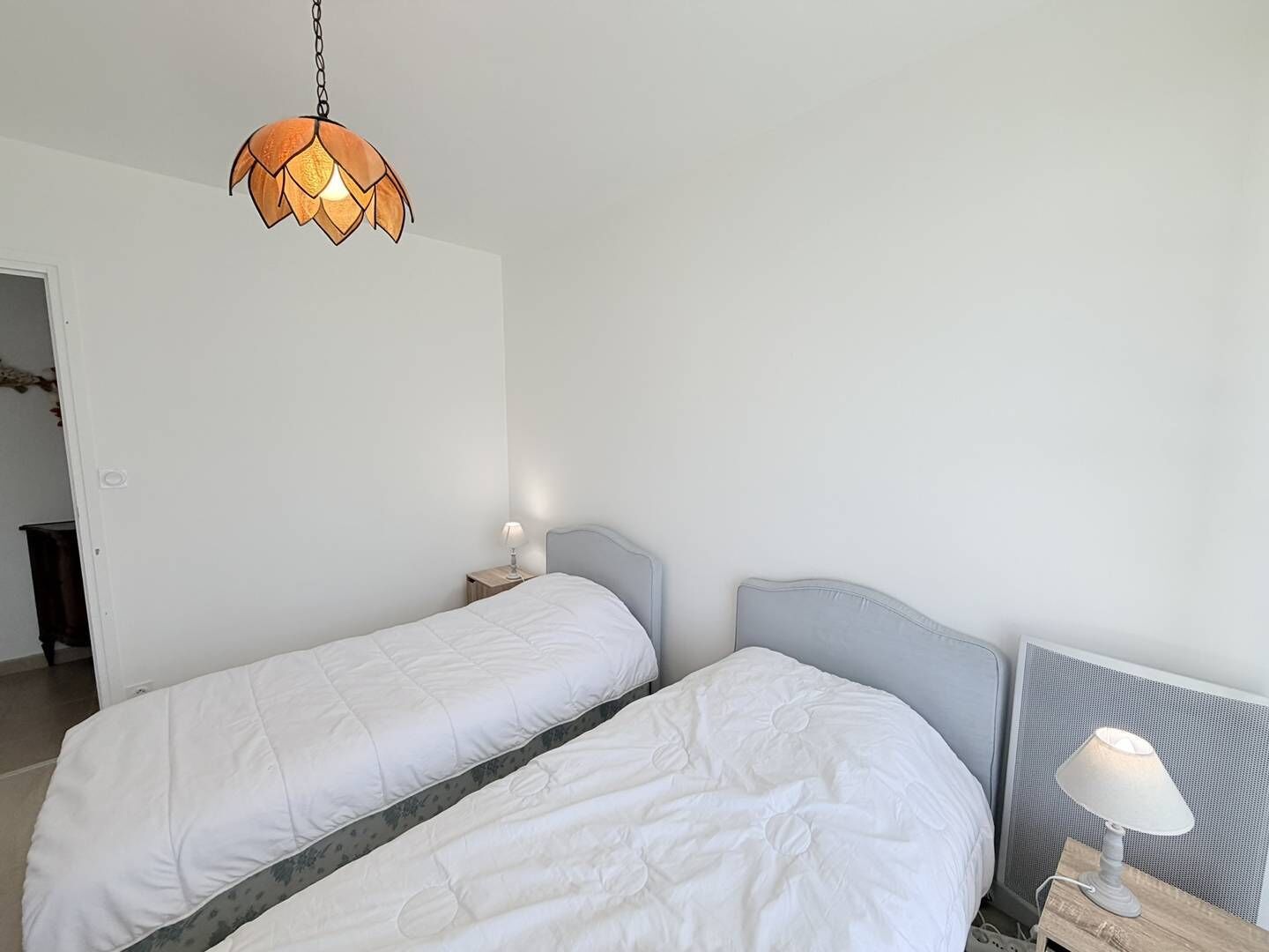 Une chambre avec deux lits simples, une table de chevet avec une lampe et un luminaire suspendu.