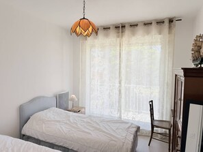 Ein Schlafzimmer mit einem Bett, einem Sessel, einem Schreibtisch mit einem Schiffsmodell und einer Hängelampe.