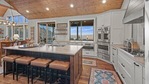 A spacious kitchen with a large island, white cabinetry, stainless steel appliances, and a wooden ceiling. - Sunbird Cabin at MontEagle - new, EV charger, hot tub, King rooms (Banner Elk)