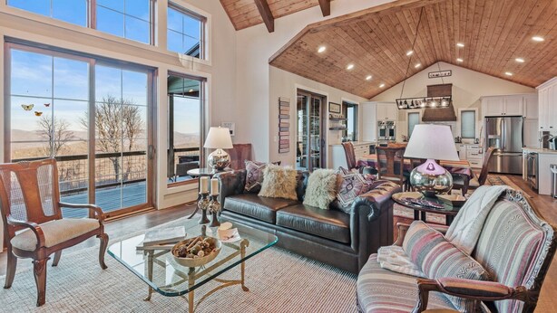 A spacious living area with a high ceiling, large windows, and a view of the outdoors. - Sunbird Cabin at MontEagle - new, EV charger, hot tub, King rooms (Banner Elk)