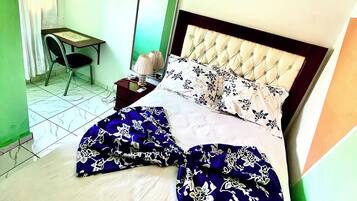 A neatly made bed with a tufted headboard, a bedside table with a lamp, and a framed picture on the wall.