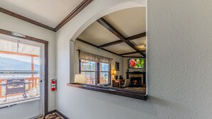 Ein gemütliches Interieur mit Kamin, Fernseher und Blick ins Freie durch ein Fenster.