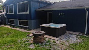 A blue house with a hot tub and a stone fire pit in the yard. - Dunes Forest Retreat (Gary)