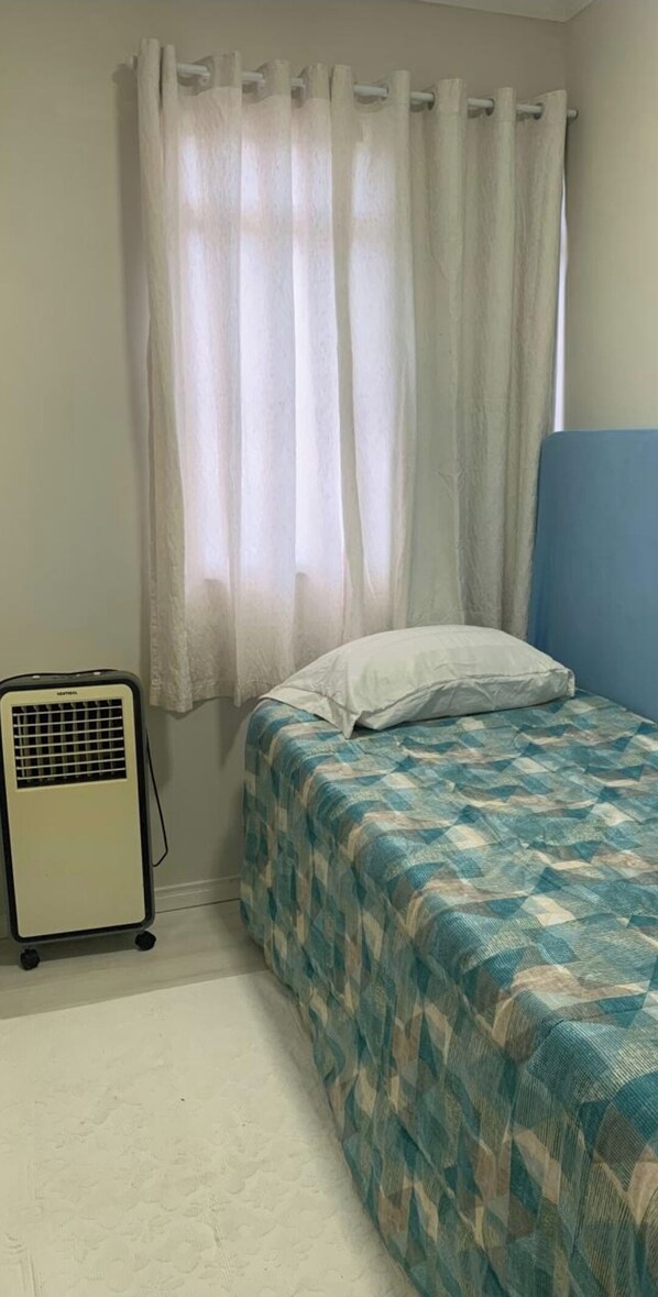 Cozy retreat with a single bed, featuring a patterned bedspread and a blue headboard.