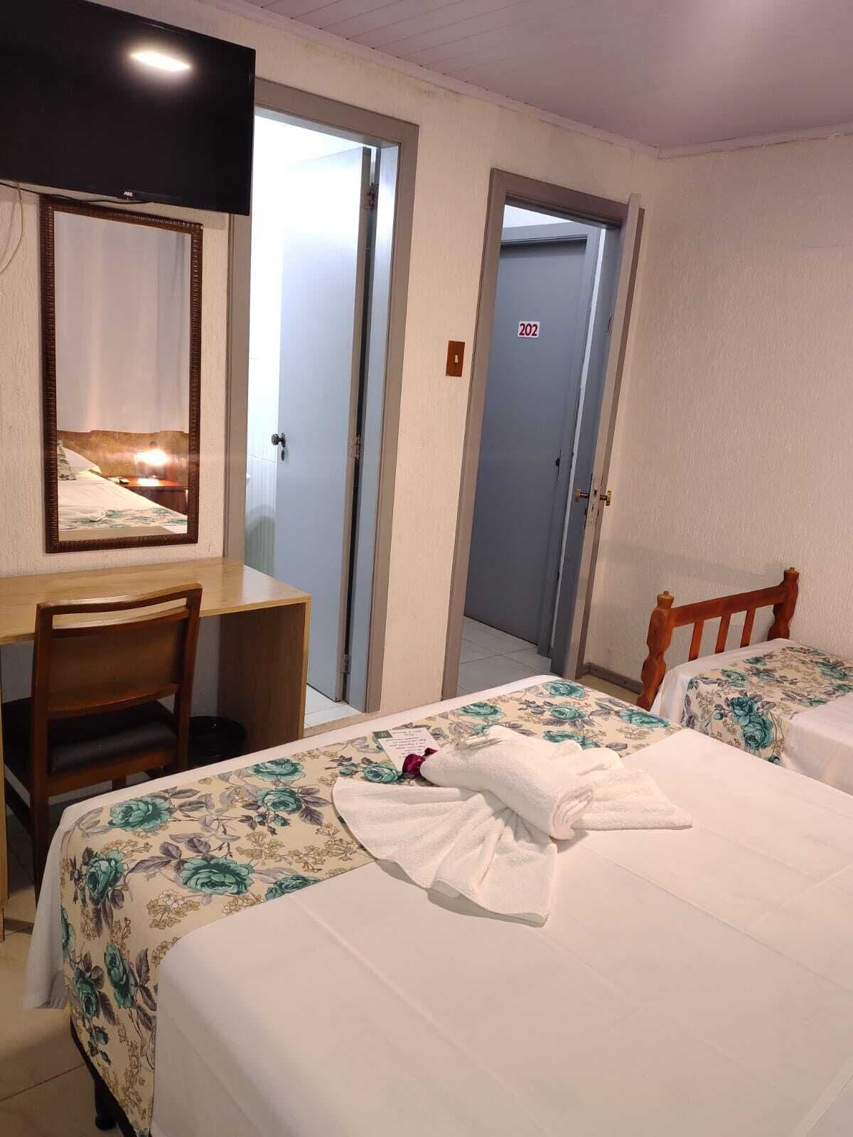 Una habitación de hotel con escritorio, dos camas, un espejo y una puerta con el número 202.