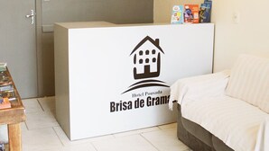 A reception desk with a sign for 'Brisa de Gramado' and a logo for 'Hotel Pousada Brisa de Gramado'. - Brisa Pousada (Gramado)