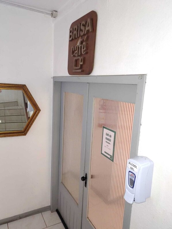 A door with a sign reading 'BRISA cafe' and a hand sanitizer dispenser on the right. - Brisa Pousada (Gramado)