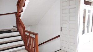 A staircase with wooden railings leading to a white door with a window. - Brisa Pousada (Gramado)