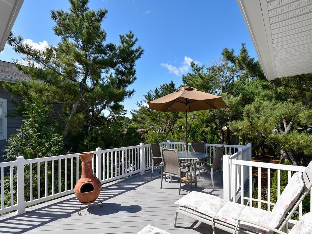 A wooden deck with outdoor furniture, including chairs and a table, and a large umbrella.