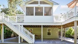 A two-story house with a covered deck, a staircase, and a large umbrella.