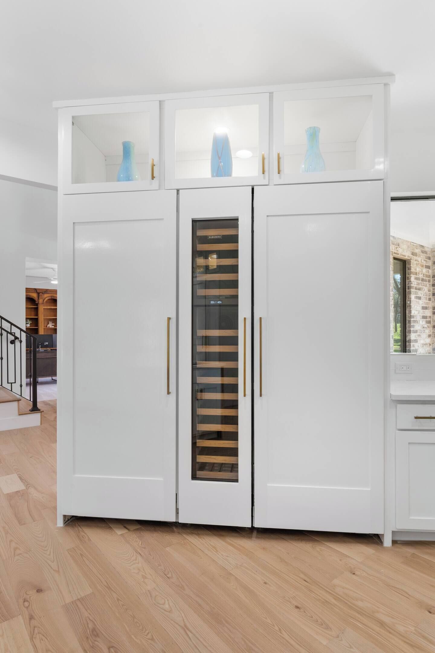 Une armoire blanche avec des portes en verre et un panneau central coulissant.