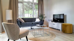 A modern living room with a sofa, a coffee table, a TV, and a plant.