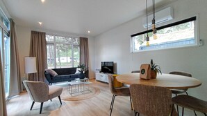 A modern living room with a sofa, TV, dining table, and chairs.