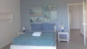 A bedroom with a bed, two bedside tables, a ceiling fan, and a door.