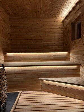 A wooden sauna with benches and a stone heater. - THE HORIZON RESIDENCE (Makubetsu)