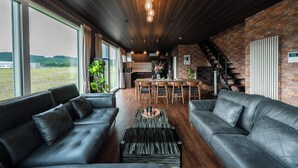 A modern living room with leather sofas, a coffee table, and a dining area with wooden chairs. - THE HORIZON RESIDENCE (Makubetsu)