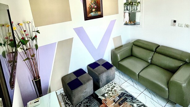 A living room with a green sofa, a coffee table, a leopard print rug, and a V-shaped wall decoration. - Studio B4 Fustel City, Bonamoussadi Santa Lucia, WiFi, canal, well, janitor  (Douala)