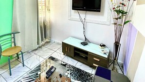 A living room with a flat-screen TV, a sofa, a coffee table, and a decorative vase. - Studio B4 Fustel City, Bonamoussadi Santa Lucia, WiFi, canal, well, janitor  (Douala)