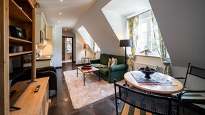 Ein gemütliches Loft-Apartment mit Essbereich, einem grünen Sofa und einem Esstisch mit einer Schüssel Tannenzapfen.