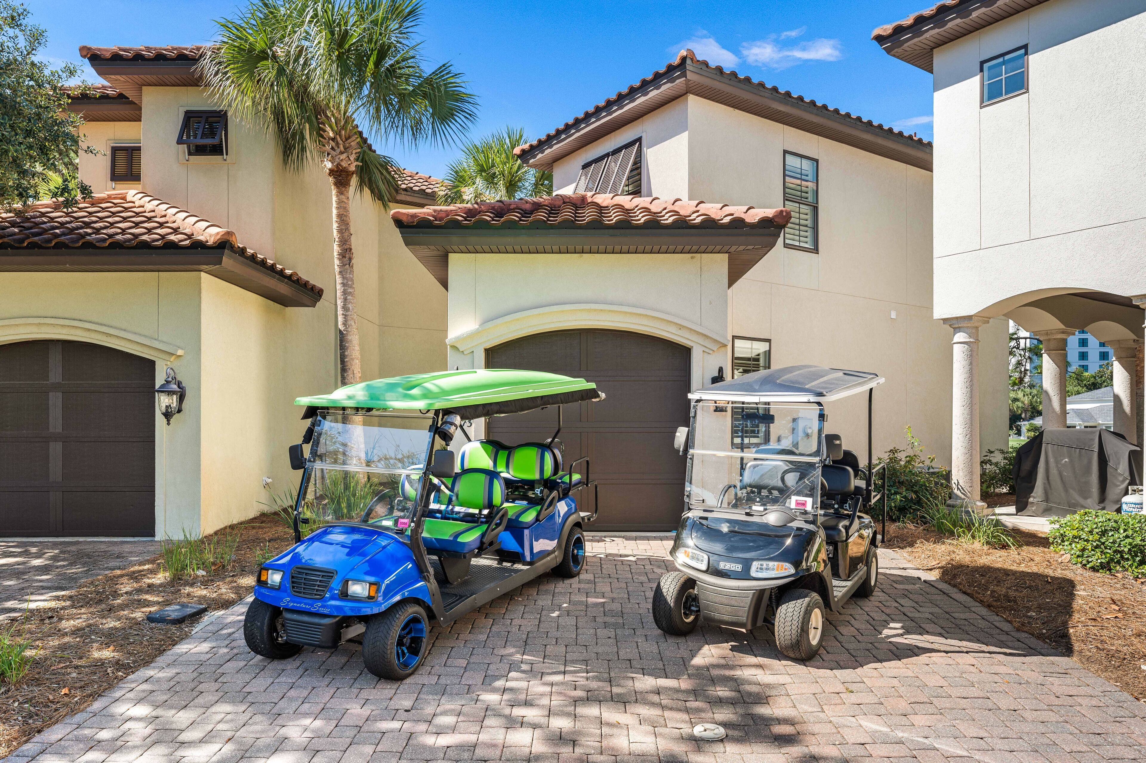 A residential area with two golf carts parked in front of a house with a brown roof and beige walls.
