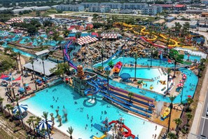 Vista aérea de um parque aquático com várias piscinas, toboáguas e uma grande área de piscina central.