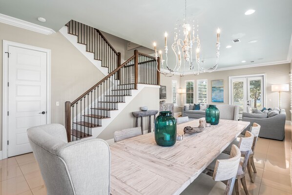 Amplia sala de estar con una mesa de comedor de madera, una escalera y un candelabro.