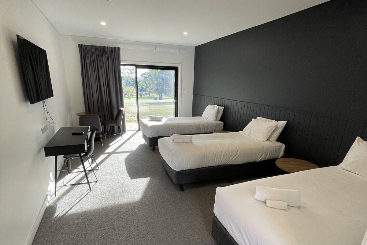 Une chambre d’hôtel avec deux lits simples, un bureau, une chaise et un téléviseur.