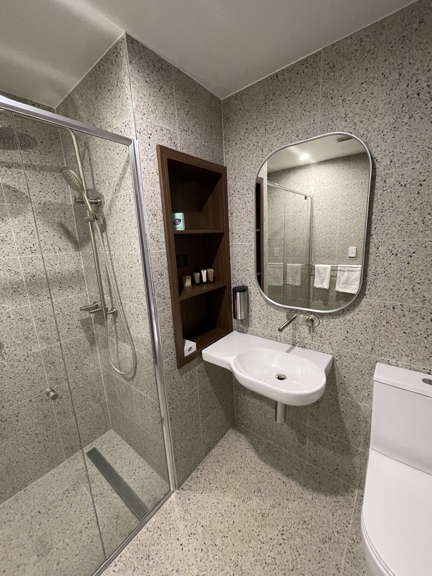 A modern bathroom with a glass-enclosed shower, a white sink, and a mirror above it.