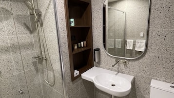A modern bathroom with a glass-enclosed shower, a white sink, and a mirror above it.
