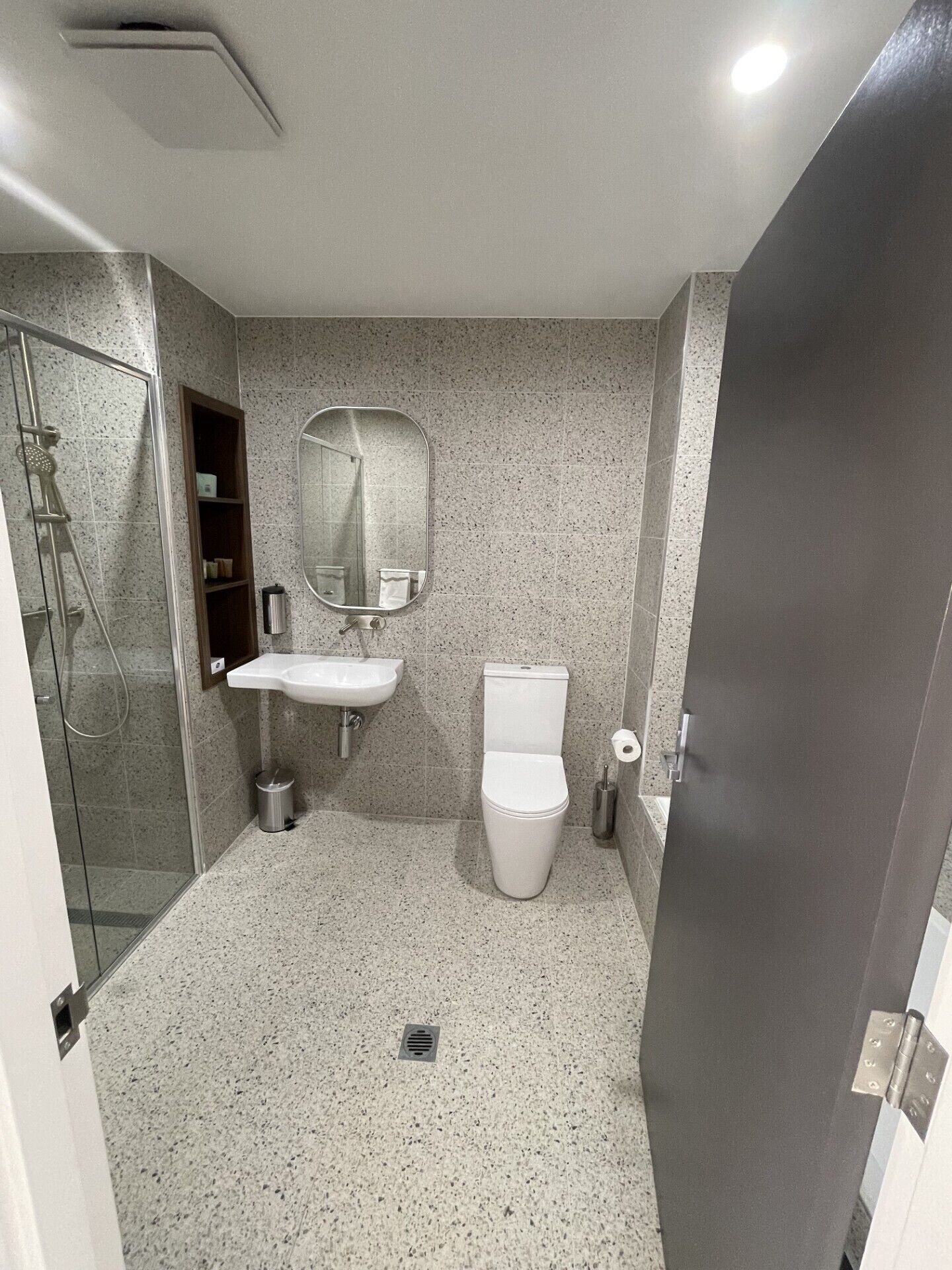 A bathroom with a shower, sink, toilet, and a mirror.
