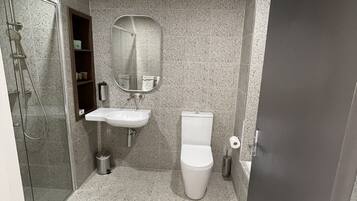 A bathroom with a shower, sink, toilet, and a mirror.