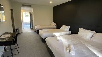 A hotel room with three beds, a desk, and a chair.