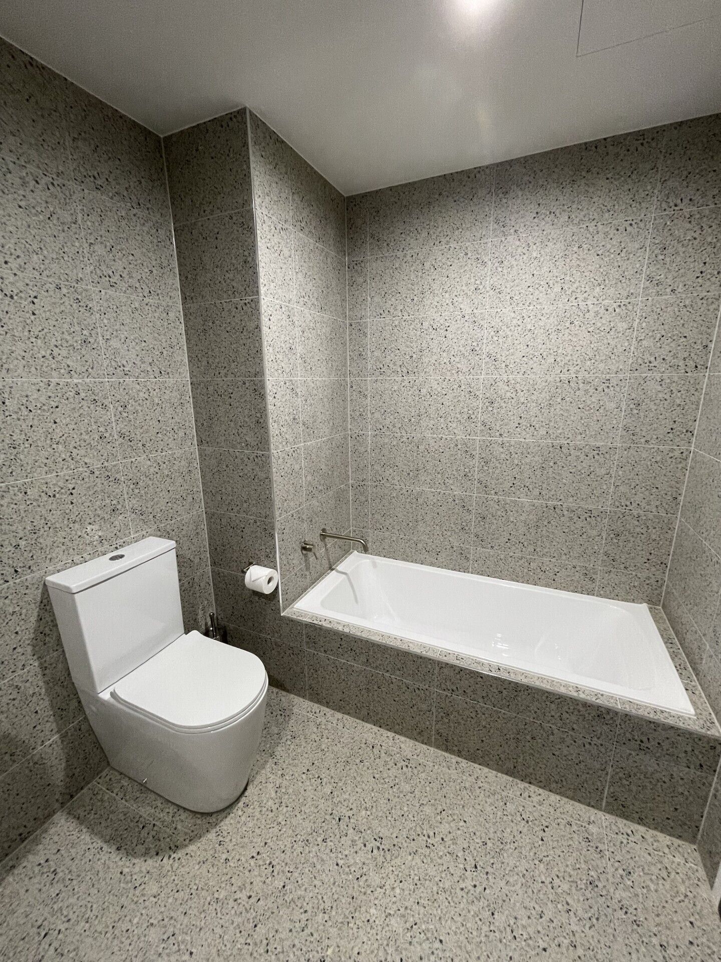 A bathroom with a toilet, a bathtub, and a shower area.