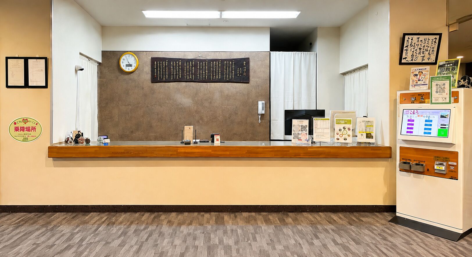 A reception area with a wooden counter, a clock, a bulletin board, and a vending machine.