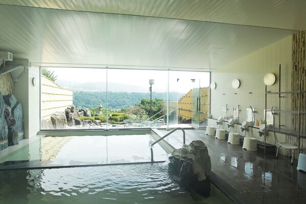 A modern indoor pool with a view of a mountainous landscape, stone features, and a series of sinks and handwashing stations. - nunobikionsen komoro (Komoro)